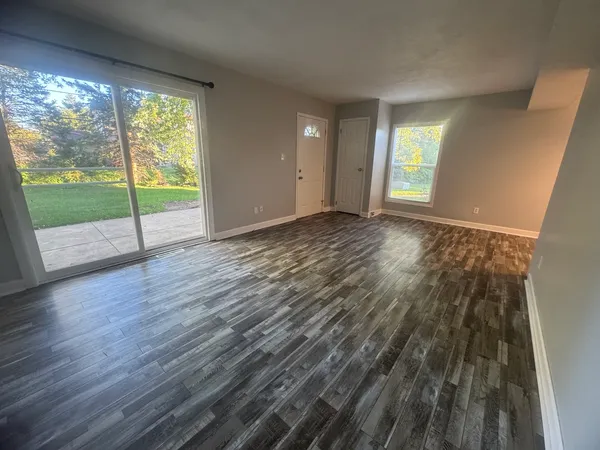 a view of an empty room with wooden floor and a window