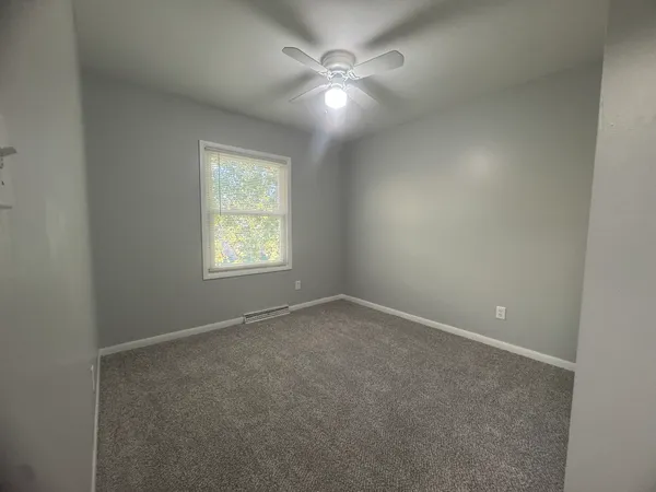 an empty room with windows and fan
