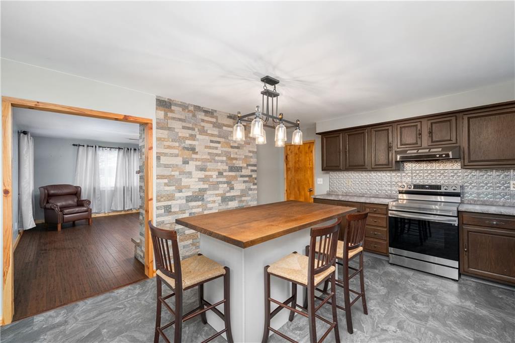222 Dick Road Prospect, PA 16052 - Photo 9 of 29 a kitchen with stainless steel appliances granite countertop a stove top oven a sink a dining table and chairs with wooden floor