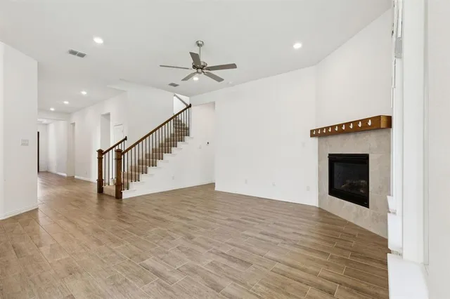 a view of an empty room with wooden floor a ceiling fan and a window