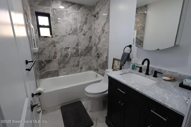 a bathroom with a double vanity sink toilet mirror and bathtub