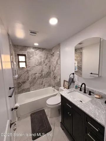 a bathroom with a granite countertop sink a toilet a mirror and bathtub