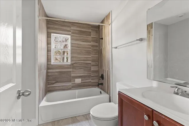 a bathroom with a granite countertop bathtub shower sink vanity and toilet