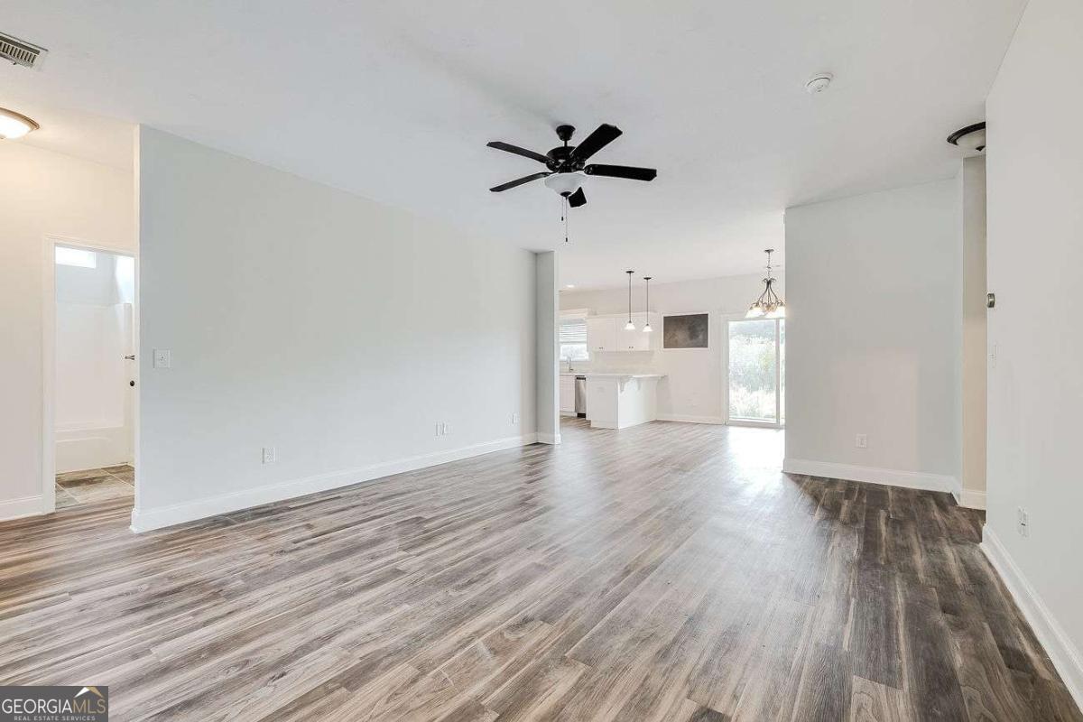 208 Timberlake Lane Guyton, GA 31312 - Photo 3 of 24 a view of a room with wooden floor a ceiling fan and windows