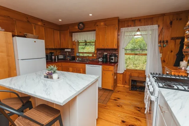 a kitchen with stainless steel appliances a stove a refrigerator a sink a dining table and chairs