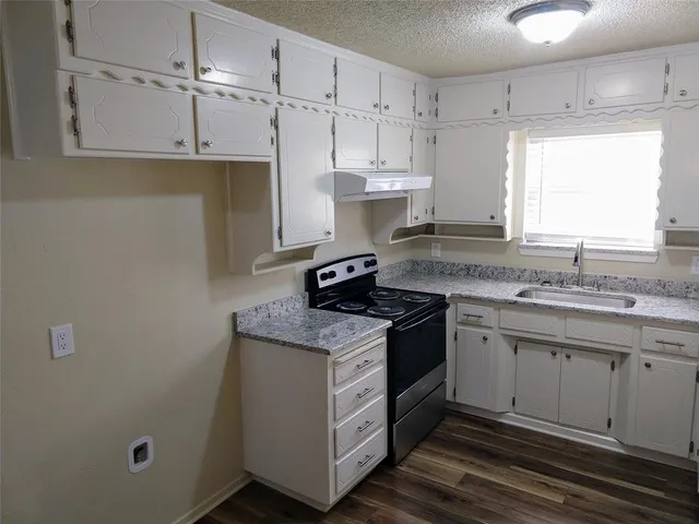 a kitchen with granite countertop a sink stove and cabinets