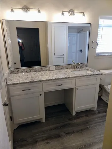 a bathroom with a granite countertop sink vanity and mirror