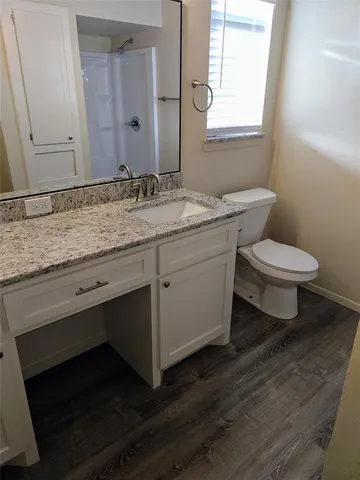 a bathroom with a granite countertop toilet sink and mirror