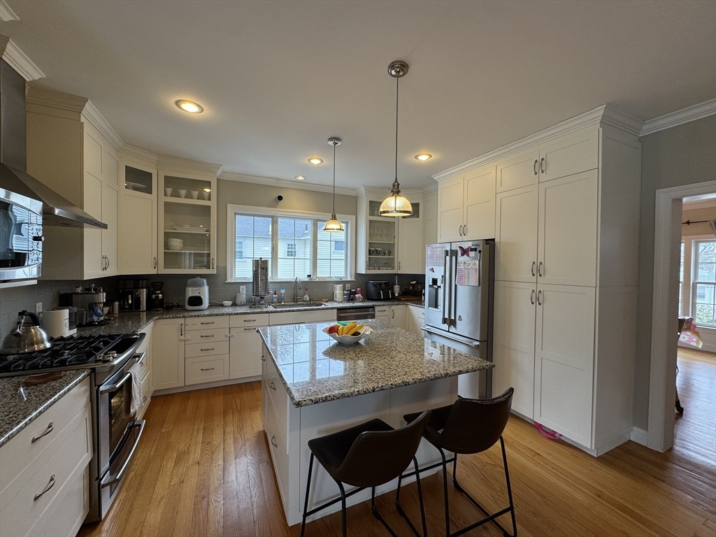 43 Canterbury Road Waltham, MA 02453 - Photo 40 of 42 a kitchen with stainless steel appliances granite countertop a refrigerator a stove top oven a sink dishwasher and a dining table with wooden floor