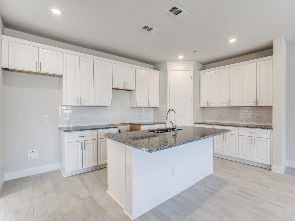 a kitchen with granite countertop white cabinets white appliances a sink and dishwasher