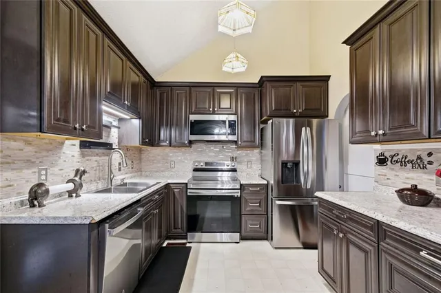 a kitchen with kitchen island granite countertop wooden cabinets stainless steel appliances and a sink