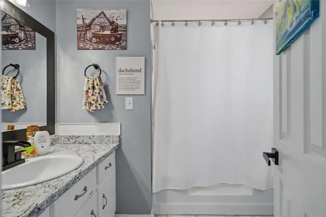 a bathroom with a granite countertop sink a mirror and shower