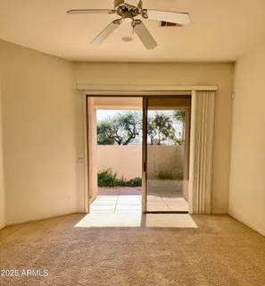 a view of a room with a floor to ceiling window and a ceiling fan