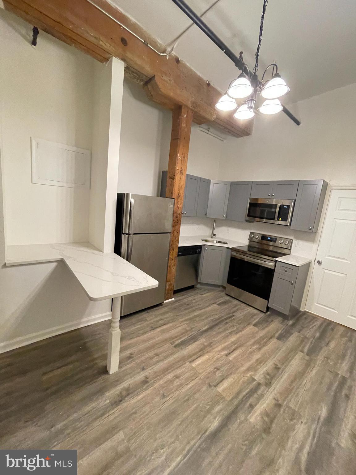 1020 Hamilton Street, Unit 4 Philadelphia, PA 19123 - Photo 9 of 19 a kitchen with stainless steel appliances a stove a refrigerator and white cabinets with wooden floor
