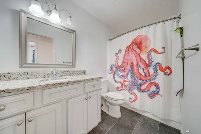 a bathroom with a granite countertop toilet sink and mirror