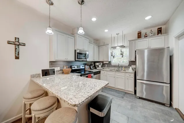 a kitchen with refrigerator a stove and chairs