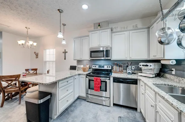 a kitchen with stainless steel appliances granite countertop a sink a stove and a wooden floors