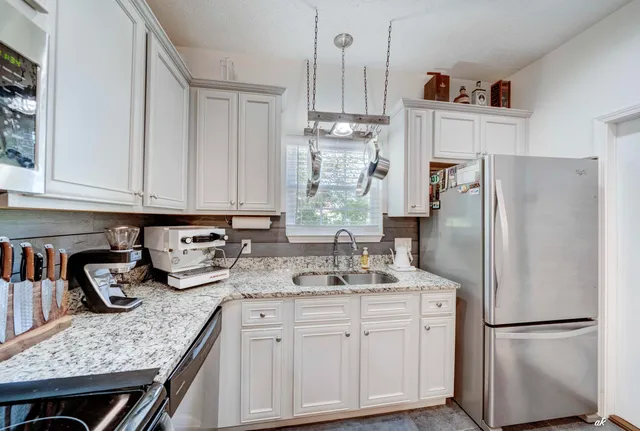 a kitchen with stainless steel appliances granite countertop a refrigerator and a sink