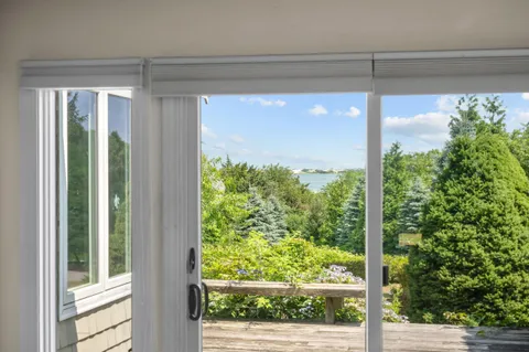a view of an empty room with wooden floor fireplace and a window
