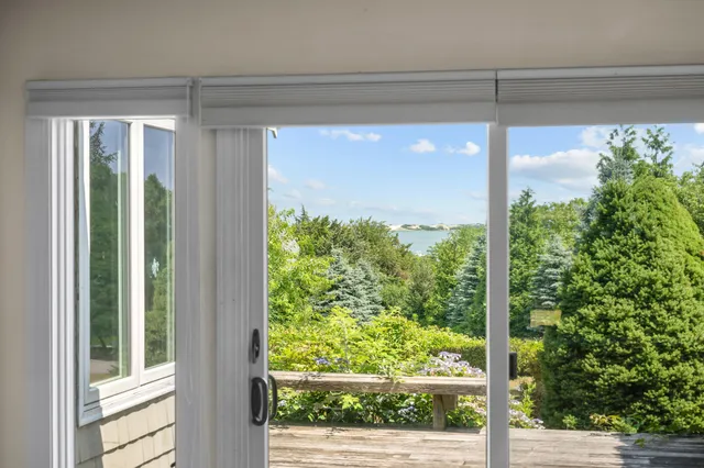 a view of an empty room with wooden floor fireplace and a window