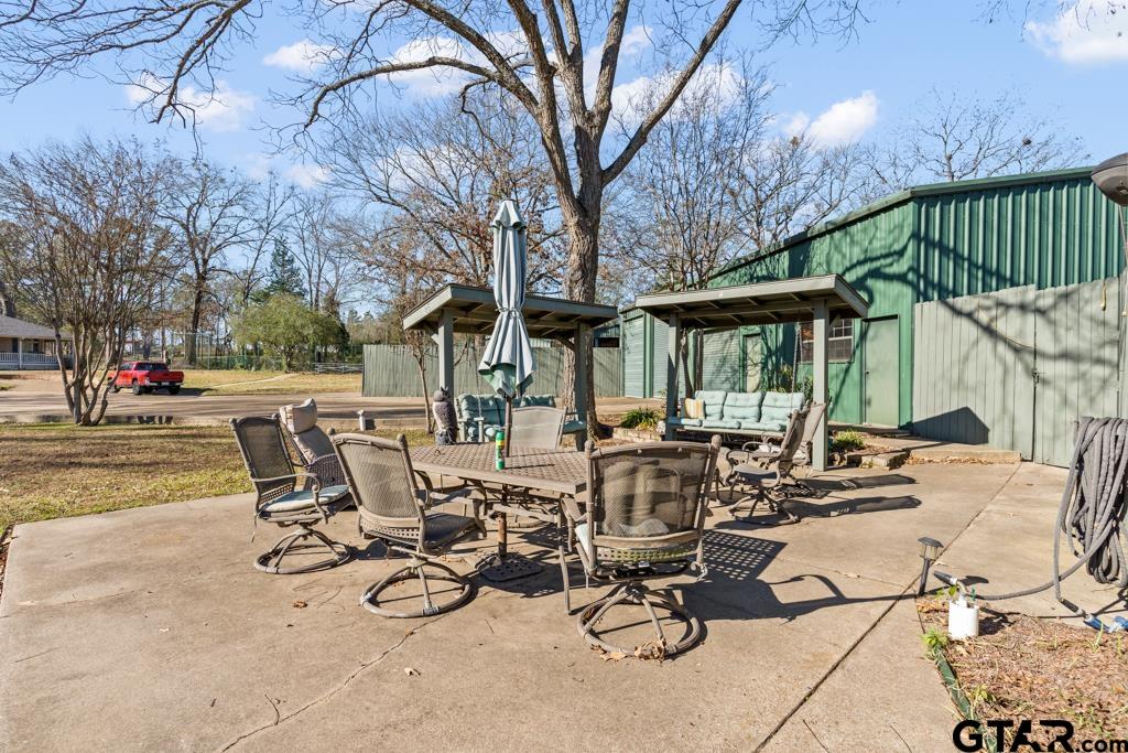 106 Cheyenne Street Gilmer, TX 75644 - Photo 41 of 48 a view of a patio with table and chairs and floor to ceiling window and wooden fence