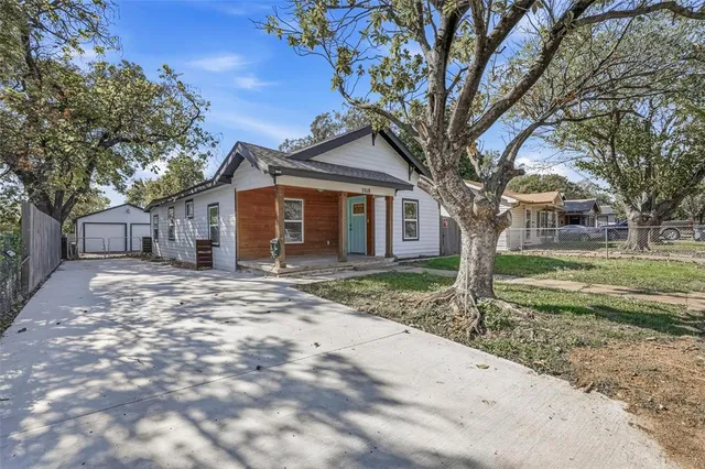 a front view of a house with a yard and large tree