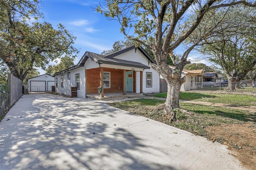 a front view of a house with a yard and large tree