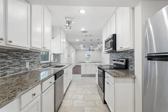 a large kitchen with stainless steel appliances granite countertop a stove a sink and a refrigerator