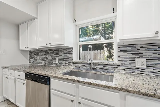 a kitchen with granite countertop a sink window and cabinets