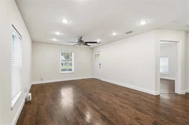 an empty room with wooden floor and windows