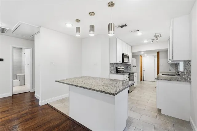 a kitchen with stainless steel appliances granite countertop a sink dishwasher and a stove with wooden floor