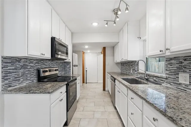 a large kitchen with granite countertop a sink and a stove