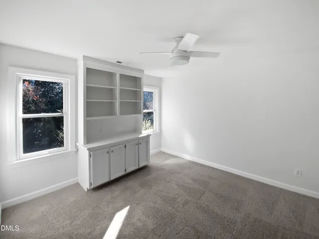 an empty room with windows and cabinet