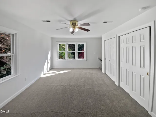 en empty room with windows and ceiling fan