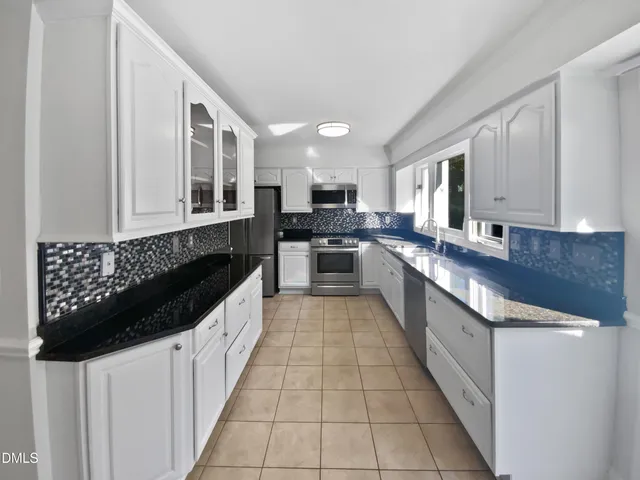 a large kitchen with stainless steel appliances a sink a stove and cabinets
