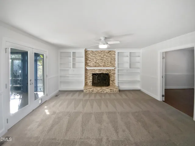 an empty room with windows and fireplace