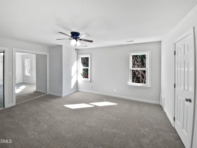a view of a big room with windows and chandelier fan
