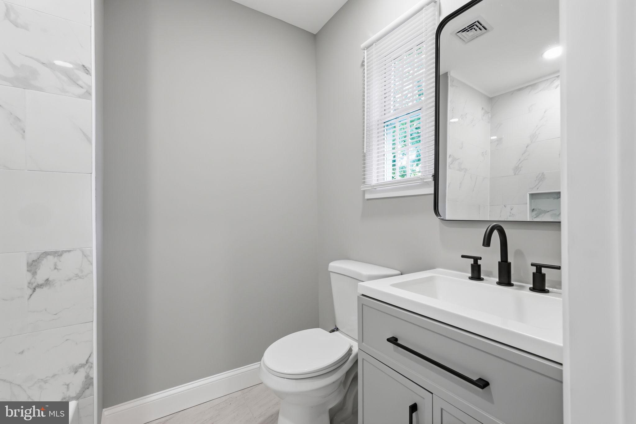 340 West Broad Street Hatfield, PA 19440 - Photo 20 of 55 a bathroom with a toilet a sink a mirror and a window