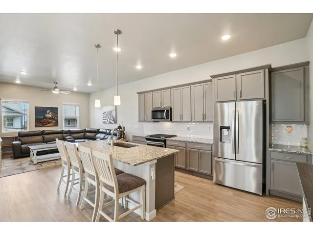 a kitchen with stainless steel appliances kitchen island granite countertop a refrigerator a stove a sink a dining table and chairs
