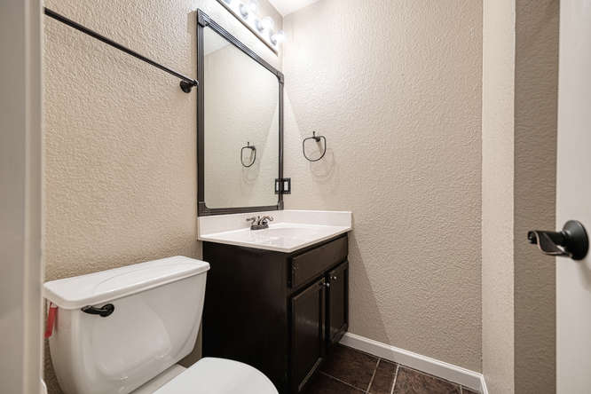 205 Polk Kyle, TX 78640 - Photo 13 of 22 Bathroom vanity with a white countertop, dark wood-finish cabinetry, and a rectangular mirror