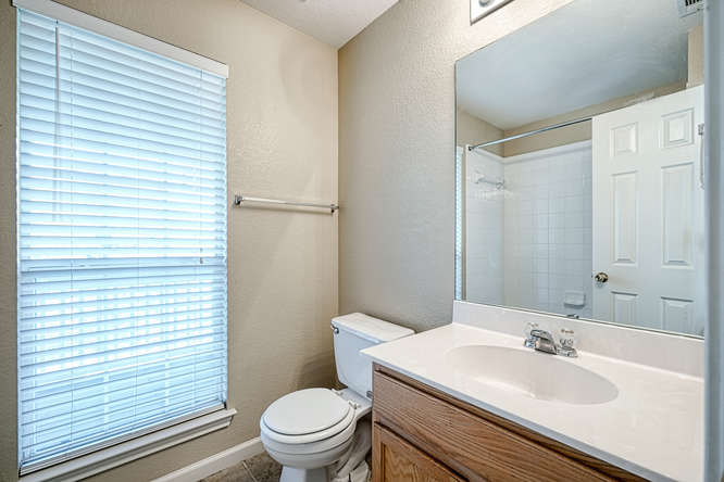 205 Polk Kyle, TX 78640 - Photo 15 of 22 Bathroom featuring a window with blinds, wood-finish vanity with an integrated sink, and a mirrored medicine cabinet