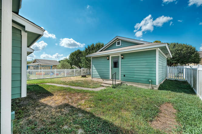 205 Polk Kyle, TX 78640 - Photo 20 of 22 Exterior auxiliary building featuring horizontal siding, white trim, a gabled roof, and two exterior light fixtures