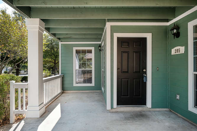 205 Polk Kyle, TX 78640 - Photo 2 of 22 Covered porch entry featuring a paneled door, exterior lighting, house numbers, and a white railing