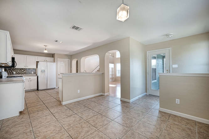 205 Polk Kyle, TX 78640 - Photo 5 of 22 Open-concept kitchen and dining area featuring ceramic tile flooring, white cabinetry, a decorative tile backsplash, and arched doorways
