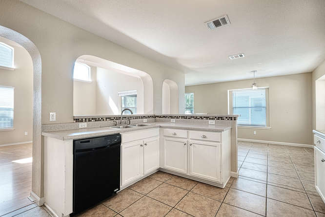 205 Polk Kyle, TX 78640 - Photo 6 of 22 Kitchen featuring white cabinetry, light-toned countertops, tile flooring, and a mosaic tile backsplash
