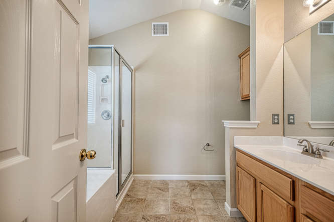 205 Polk Kyle, TX 78640 - Photo 10 of 22 Bathroom featuring a glass-enclosed shower, tiled flooring, wood vanity with integrated sink, large wall mirror, and vaulted ceiling