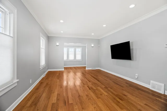 a view of empty room with wooden floor and fan