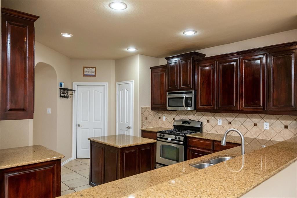 7607 Yearling Way Arlington, TX 76002 - Photo 8 of 25 a kitchen with stainless steel appliances granite countertop a stove a sink and a microwave