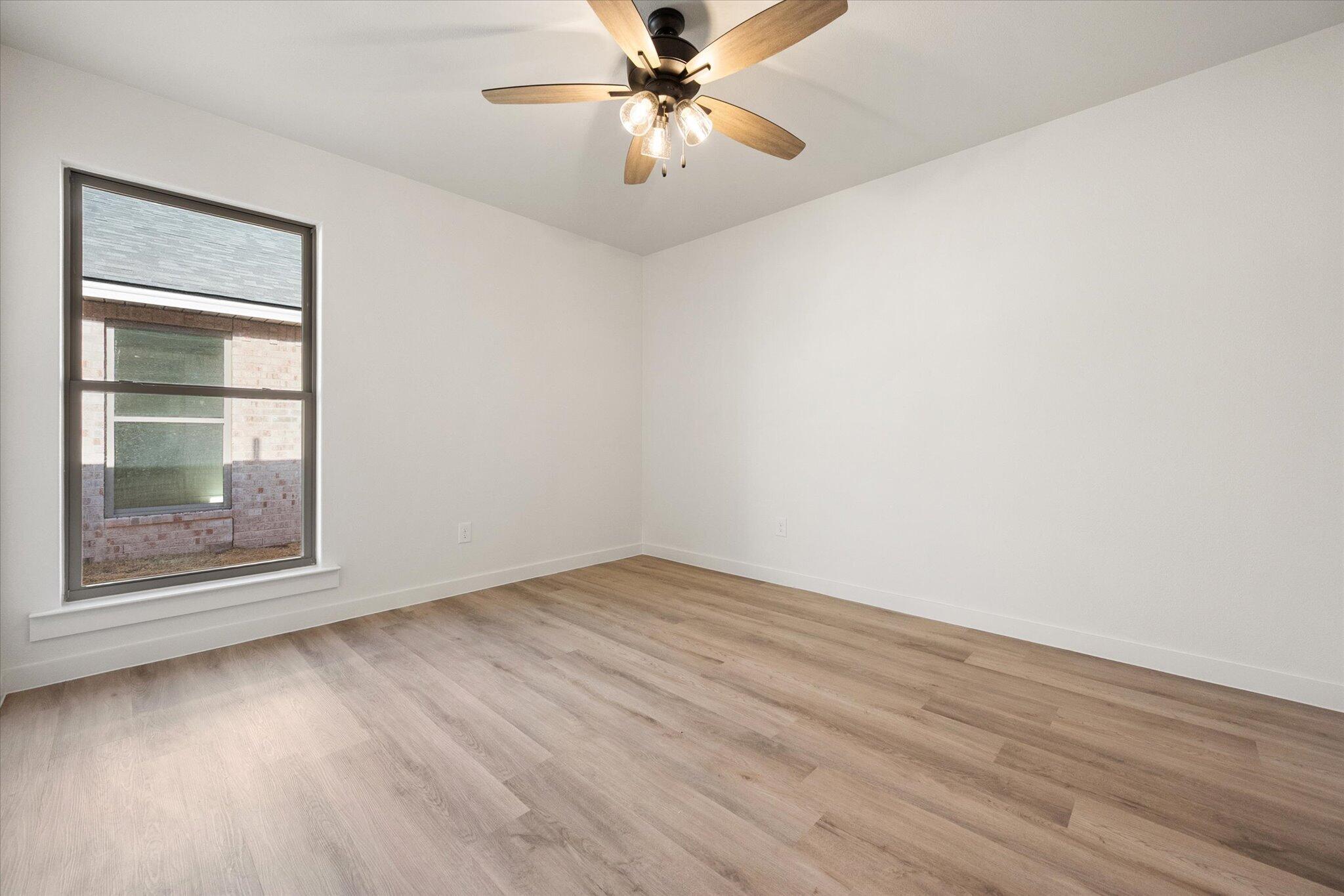 6925 53rd Street Lubbock, TX 79407 - Photo 18 of 22 an empty room with wooden floor fan and windows