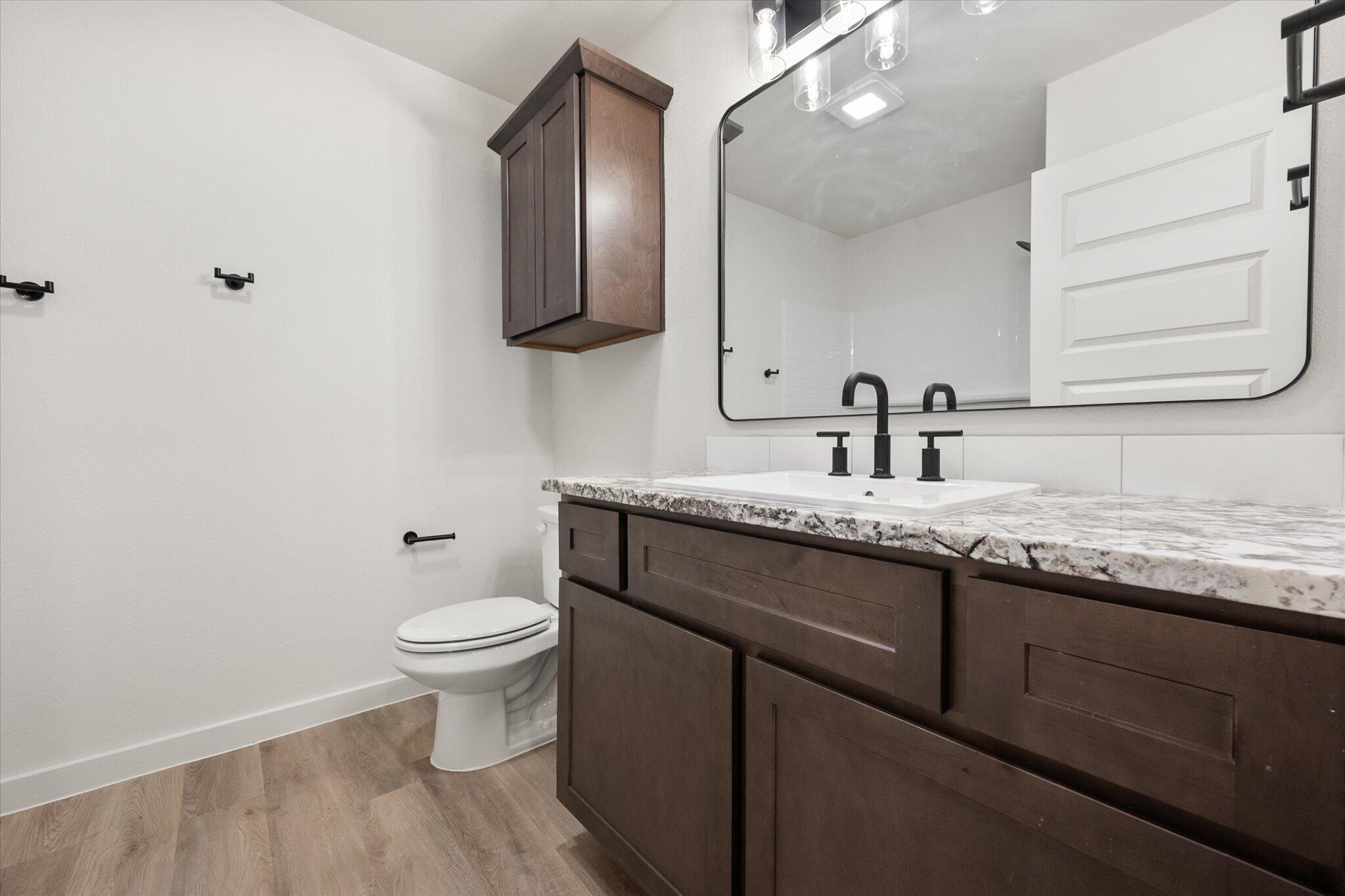 6925 53rd Street Lubbock, TX 79407 - Photo 19 of 22 a bathroom with a granite countertop sink a toilet and mirror
